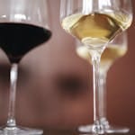 Close-up of elegant wine glasses filled with red and white wine in a blurred background setting.