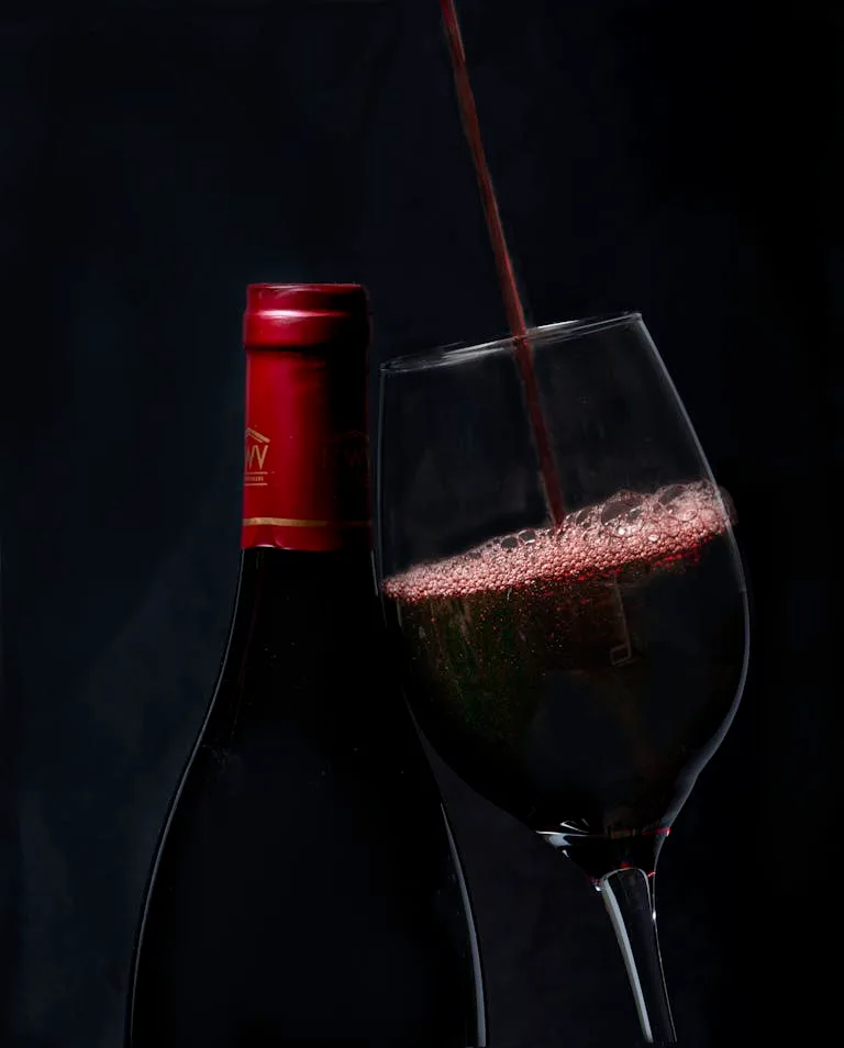 Elegant red wine pouring into a glass with a bottle in background, perfect for wine enthusiasts.